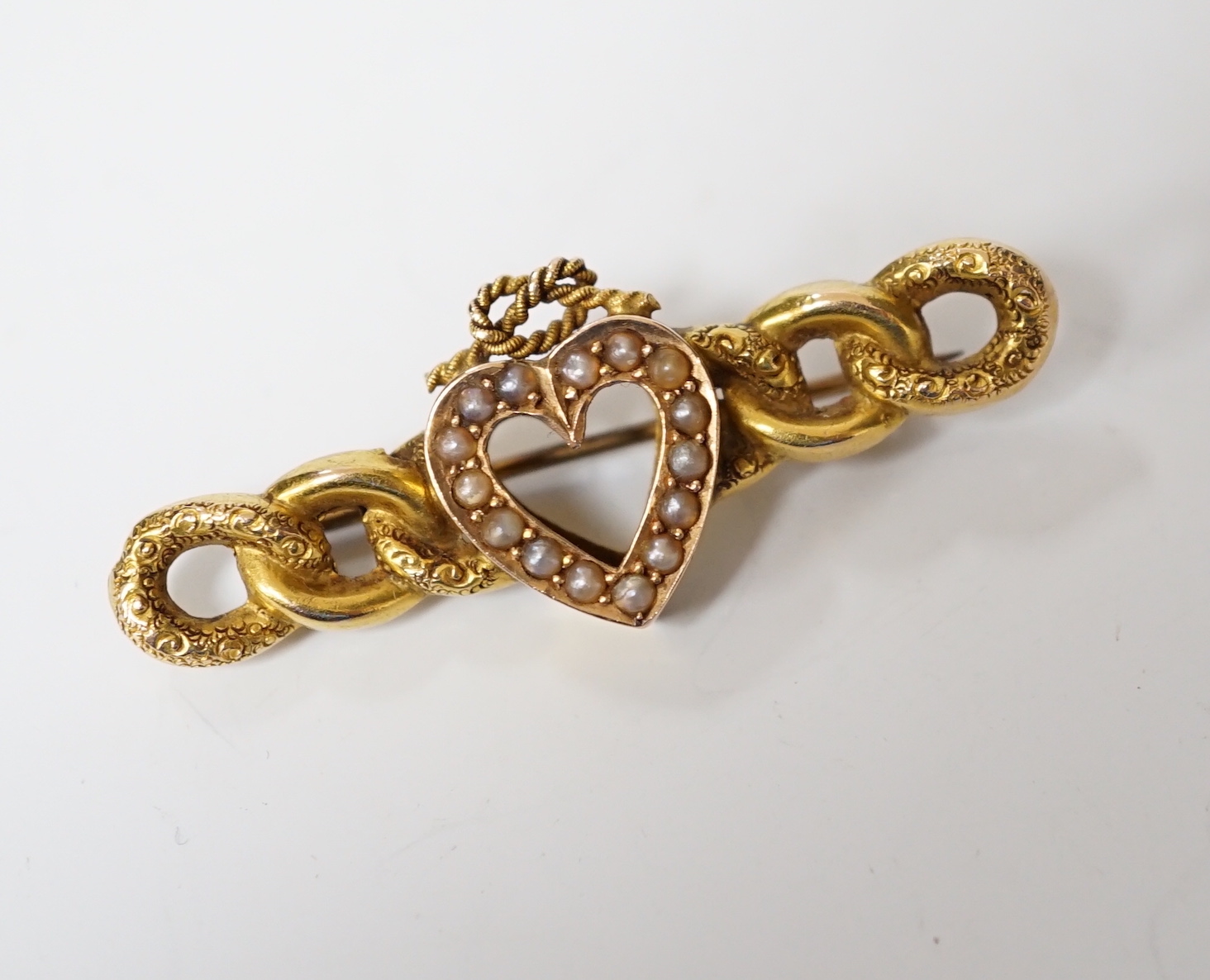 A late Victorian 15ct gold and seed pearl set bar brooch, with central heart with knot motif, 43mm, gross weight 3.8 grams.